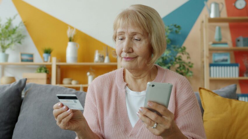 Elderly woman holding credit card and smartphone